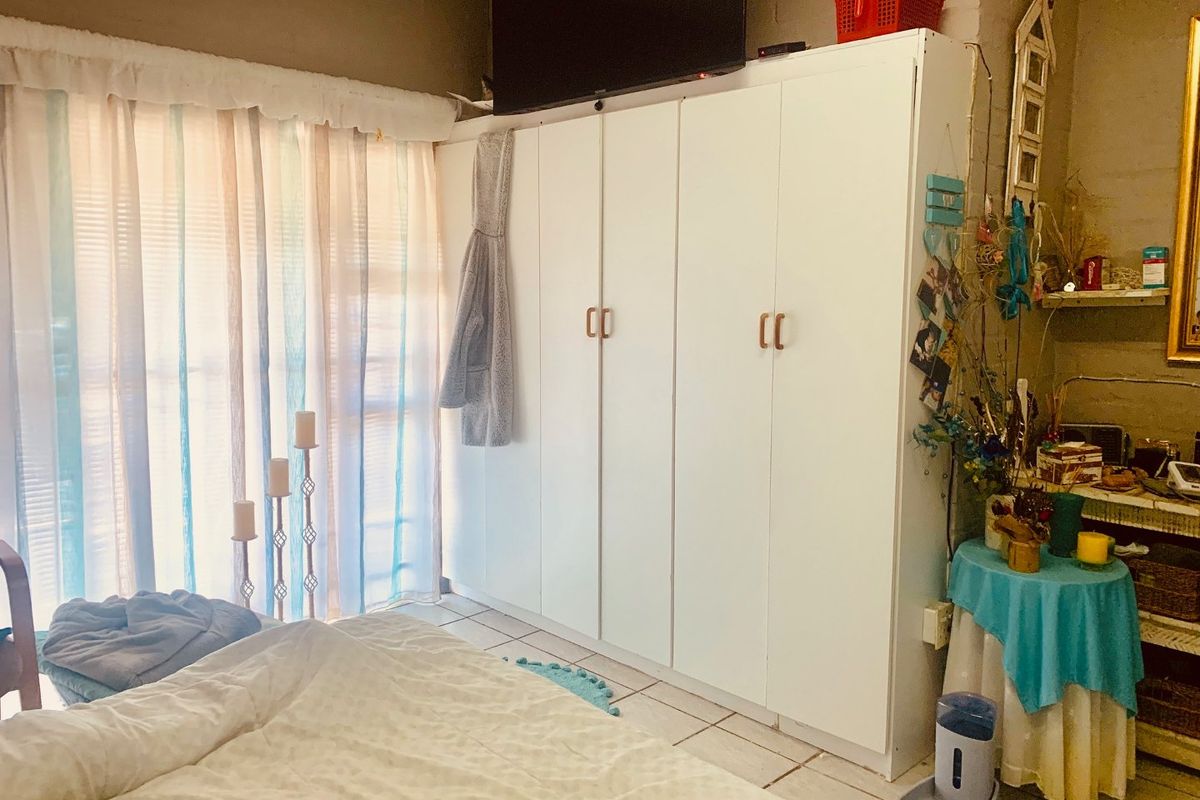 A bedroom featuring a large white built-in wardrobe and tiled flooring, providing ample storage space.