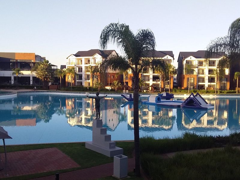 A well-maintained communal swimming pool area surrounded by landscaped gardens and modern multi-story apartment buildings.