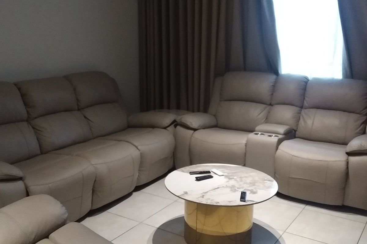 A comfortable living room area featuring neutral tiled flooring and floor-to-ceiling curtains, providing a clean and functional space.