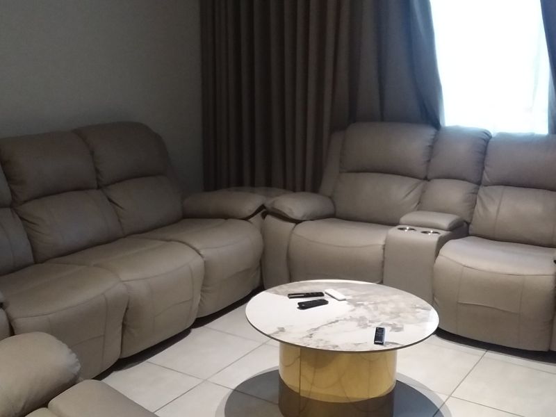 A comfortable living room area featuring neutral tiled flooring and floor-to-ceiling curtains, providing a clean and functional space.