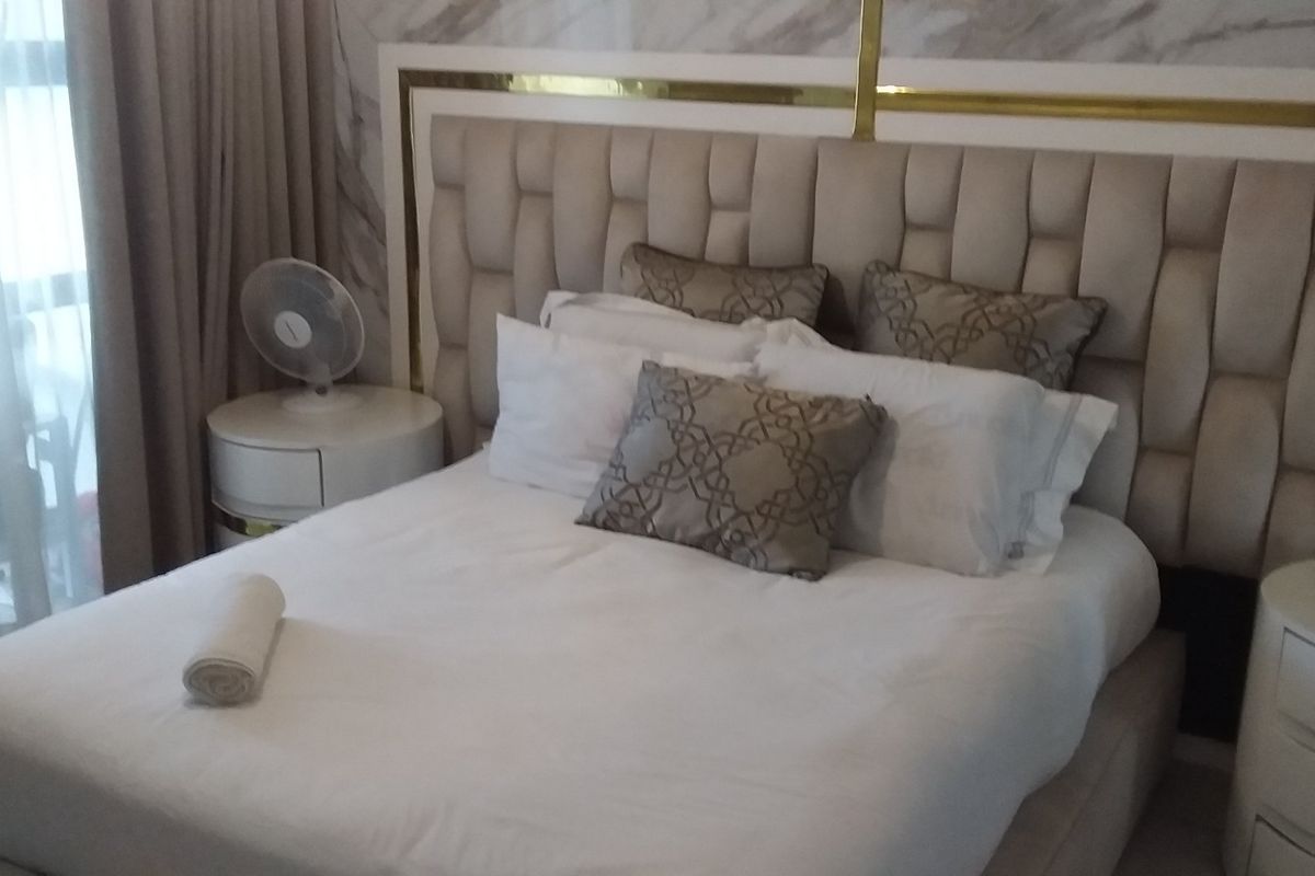 A well-appointed bedroom featuring a large upholstered headboard and decorative marble-effect wall paneling.