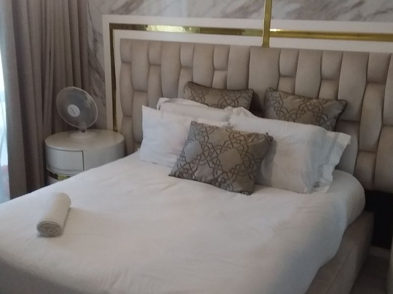 A well-appointed bedroom featuring a large upholstered headboard and decorative marble-effect wall paneling.