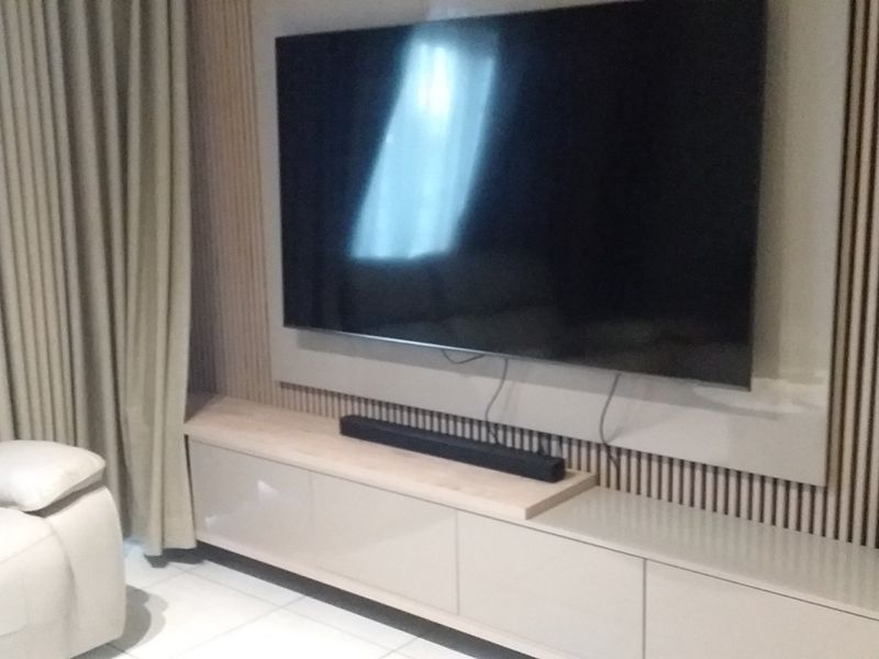 A modern living room featuring a custom built-in media console and decorative slatted timber wall paneling.