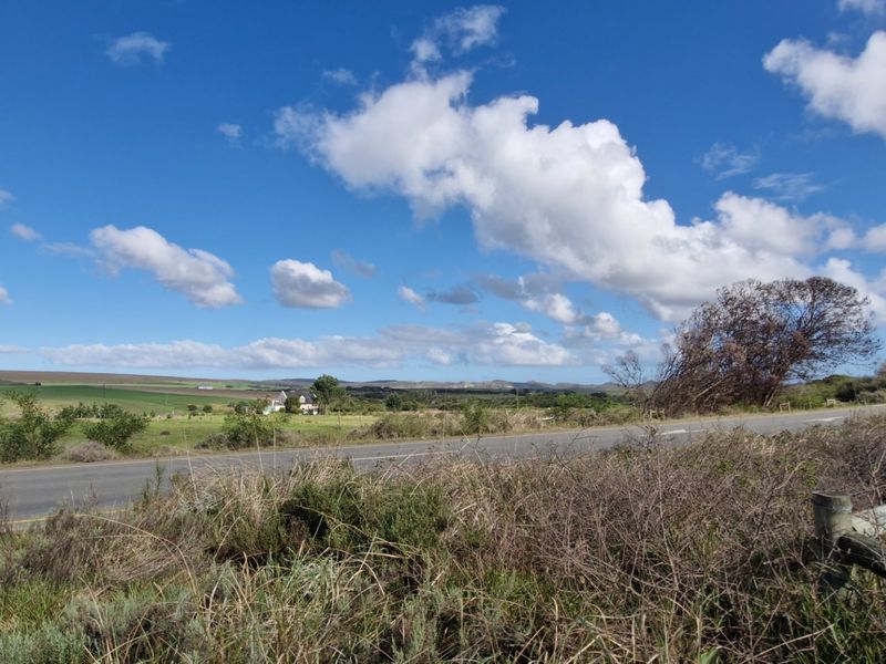A view of the rural landscape and asphalt road approach leading towards the farm property.