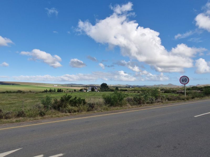 A view of the property from the adjacent asphalt road, showcasing the surrounding rural landscape and open fields.