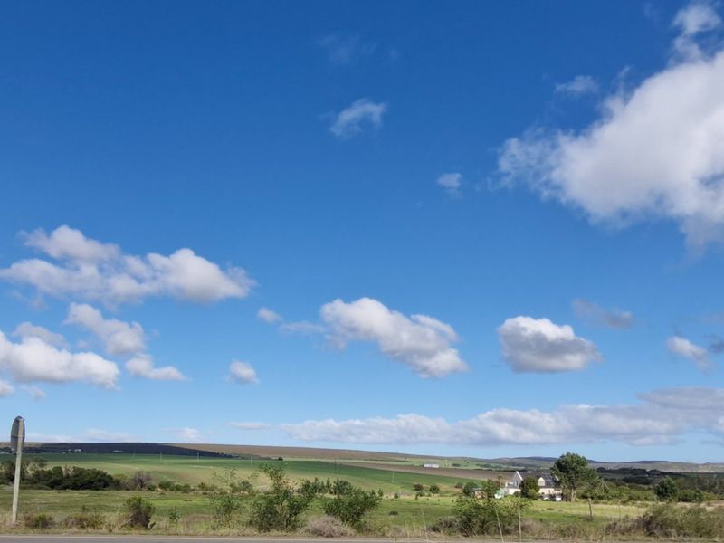 A scenic view of the expansive farm landscape under a clear blue sky with rolling hills and open fields.