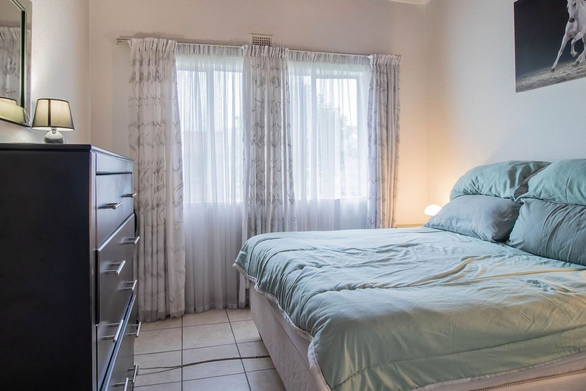 A functional bedroom featuring tiled flooring and large windows with curtain tracks, providing natural light and a neutral base for interior design.