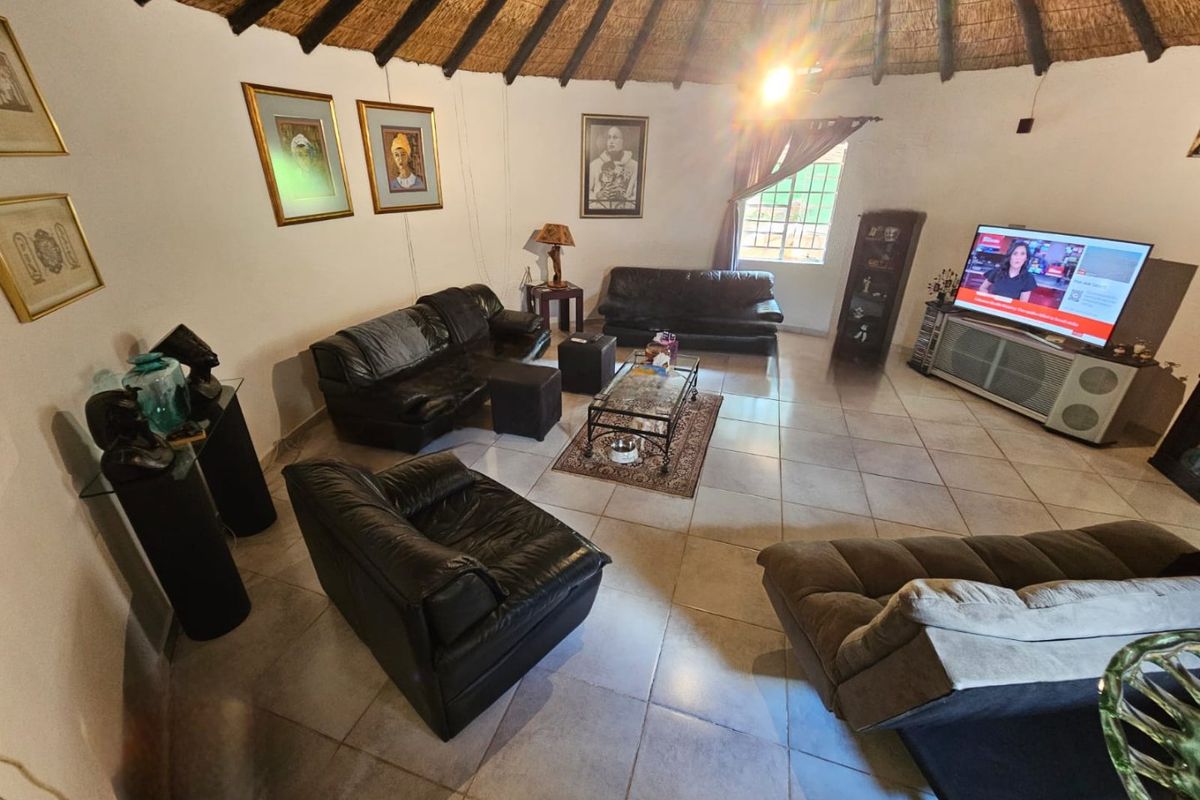 Spacious living area featuring a traditional thatched roof with exposed timber rafters and neutral tiled flooring, creating a rustic and inviting atmosphere.
