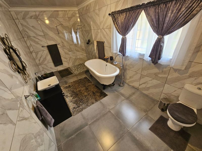 Modern bathroom featuring a freestanding bathtub, walk-in shower, vessel sink vanity, and neutral floor-to-ceiling tiling.
