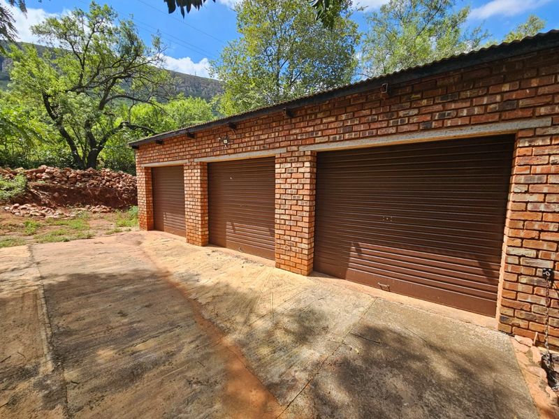 A triple garage featuring face brick construction, brown roller shutter doors, and a corrugated metal roof, situated on a concrete driveway.