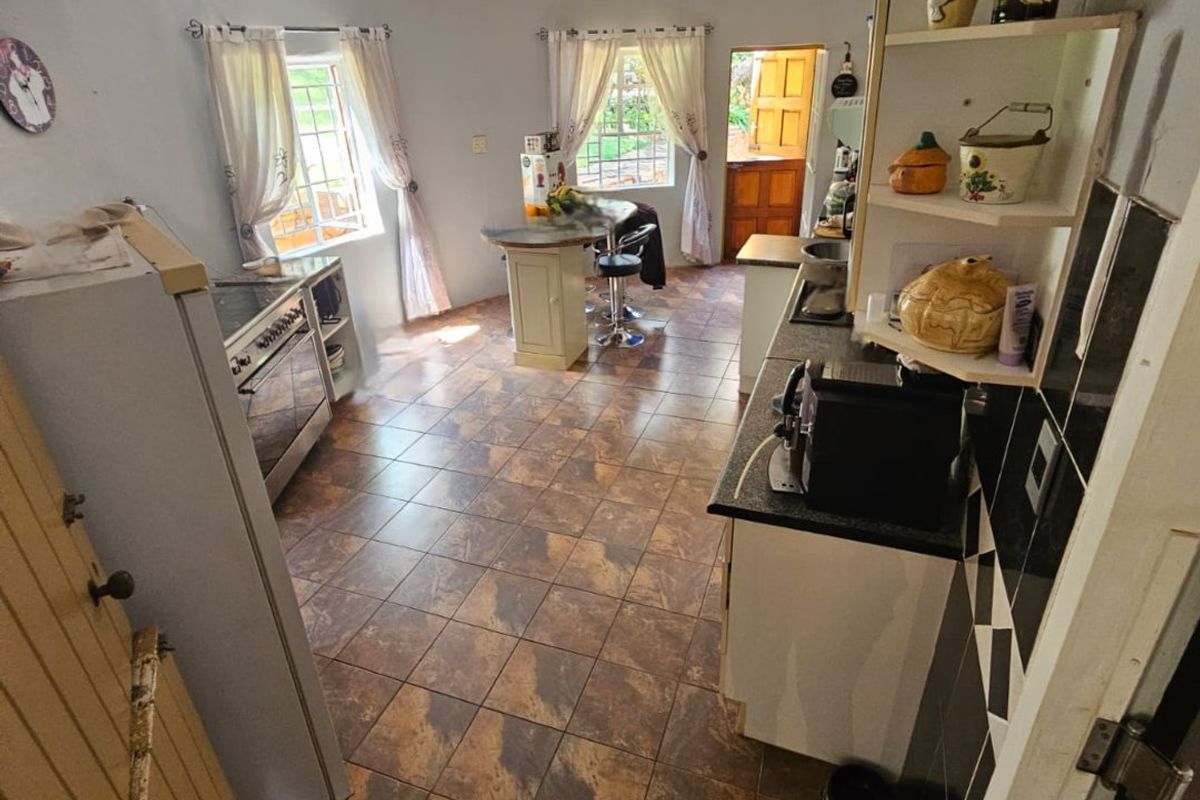 A functional kitchen featuring tiled flooring, built-in cabinetry, a central island, and a freestanding stove with direct access to the exterior.