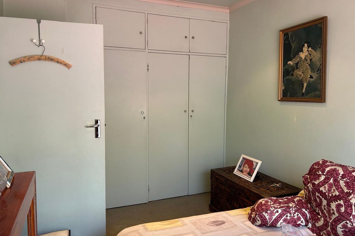 A bedroom featuring built-in cupboards with integrated overhead storage cabinets and decorative coving.