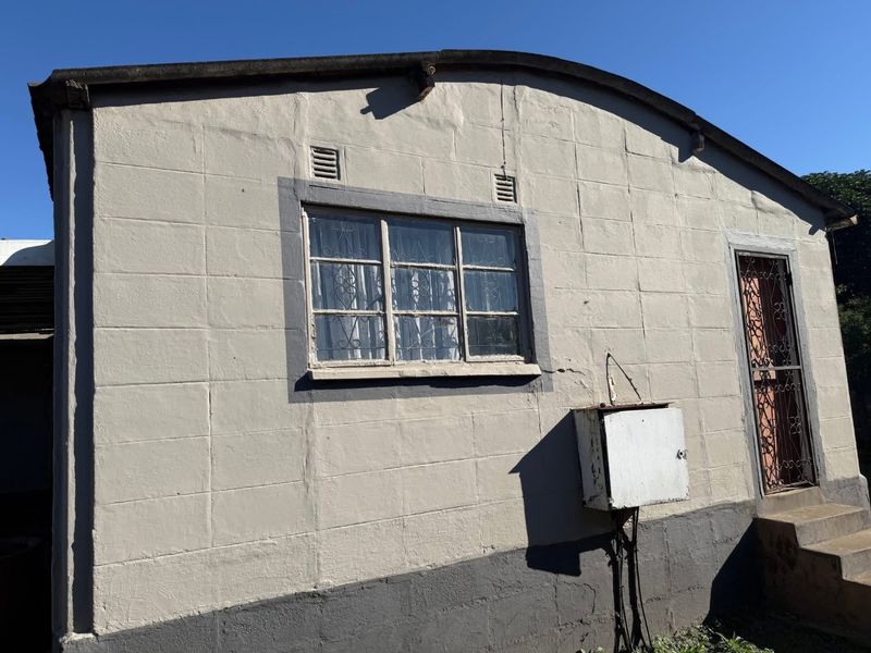 Exterior view of the rear building facade featuring concrete block construction, a security gate, and an external electrical distribution box.
