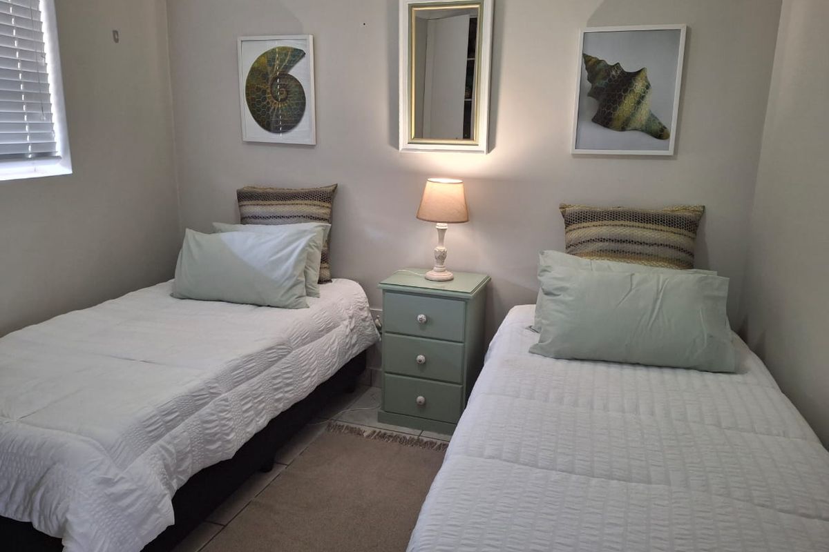 A functional bedroom featuring tiled flooring and venetian blinds, currently configured with twin beds.
