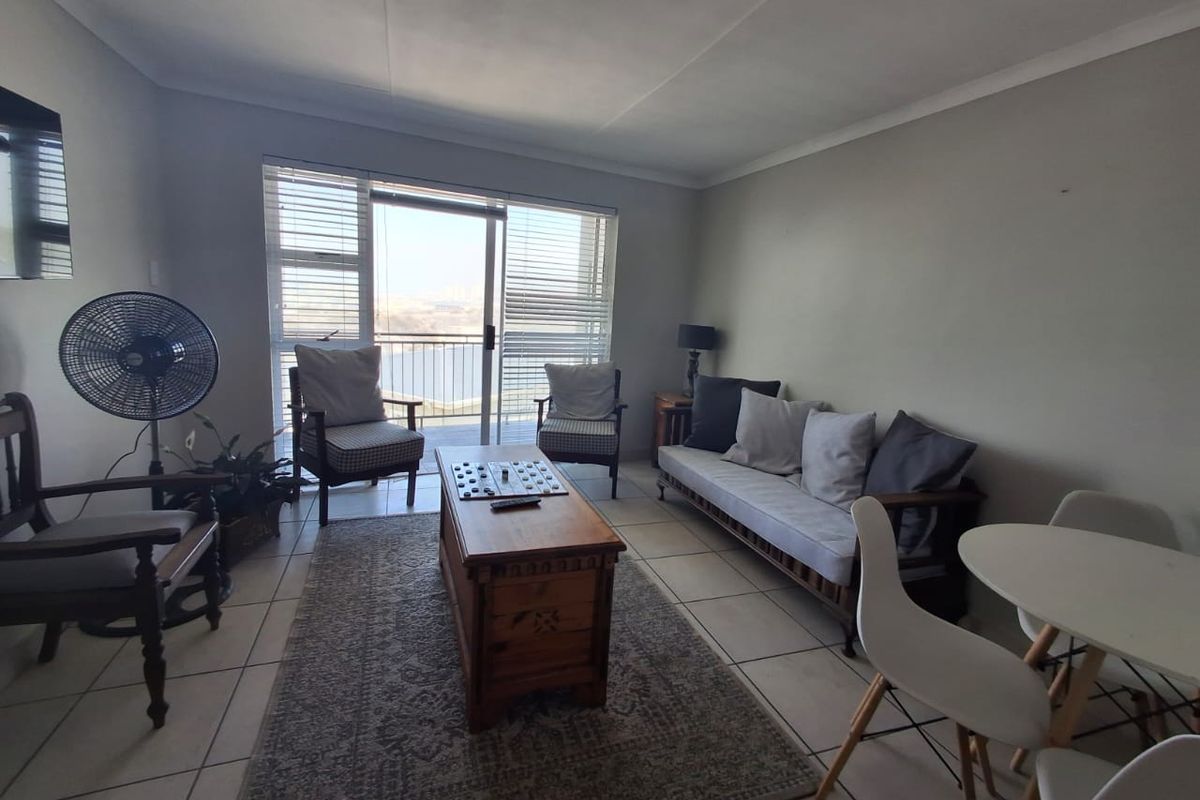 A bright living room featuring neutral tiled flooring and a large sliding glass door that provides natural light and access to the balcony.