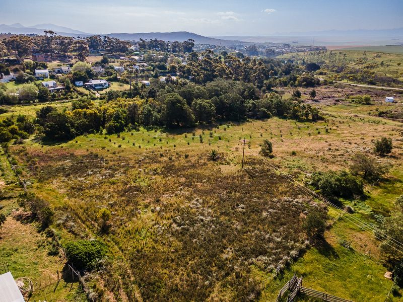 An aerial view of a large, undeveloped residential plot featuring natural vegetation, perimeter fencing, and overhead power lines with surrounding rural landscape.