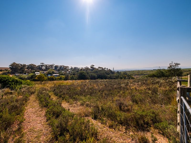 Expansive view over undeveloped residential land featuring natural vegetation, an unpaved access track, and perimeter timber and wire fencing.