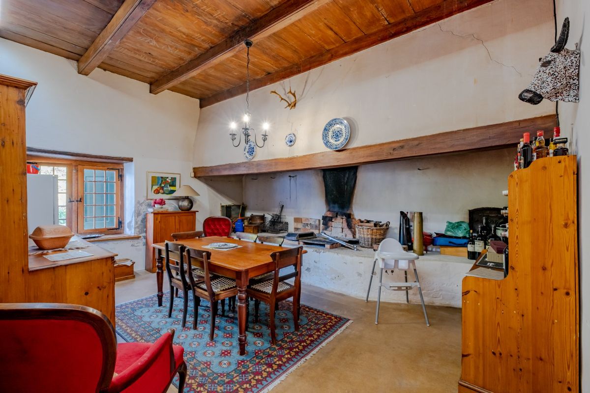 Rustic farmhouse kitchen featuring a large traditional masonry hearth, exposed timber ceiling beams, and classic casement windows.