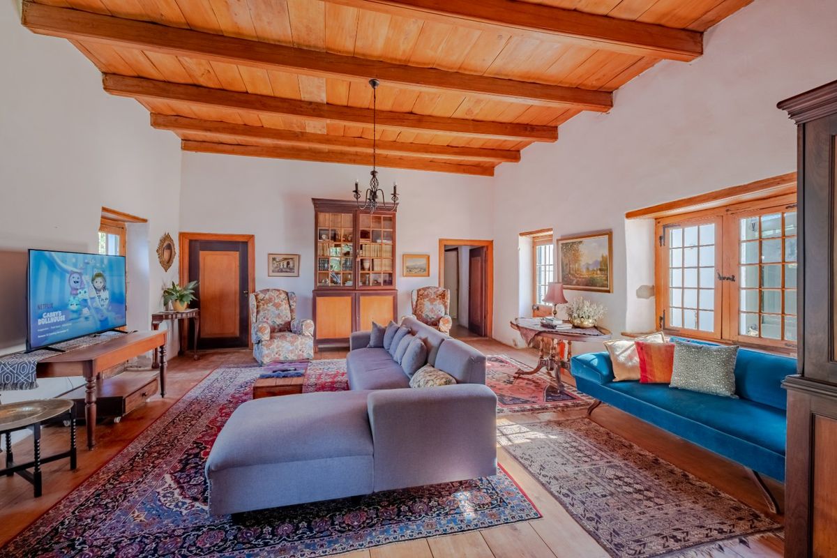 Spacious living room featuring exposed timber ceiling beams, warm timber flooring, and classic timber-framed windows, creating a rustic and inviting atmosphere.