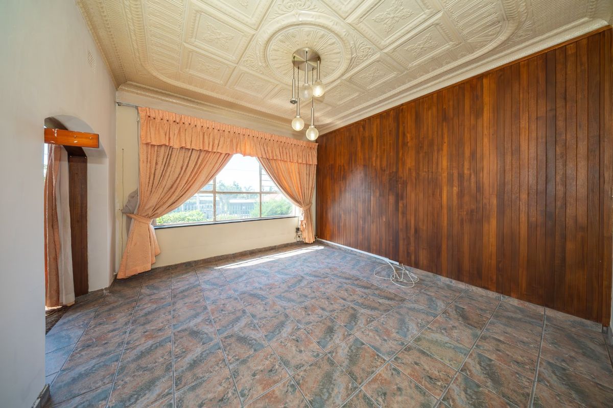 Spacious living area featuring unique decorative pressed metal ceilings, warm timber wall paneling, and durable tiled flooring, offering a classic aesthetic.