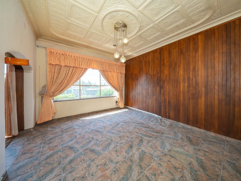 Spacious living area featuring unique decorative pressed metal ceilings, warm timber wall paneling, and durable tiled flooring, offering a classic aesthetic.