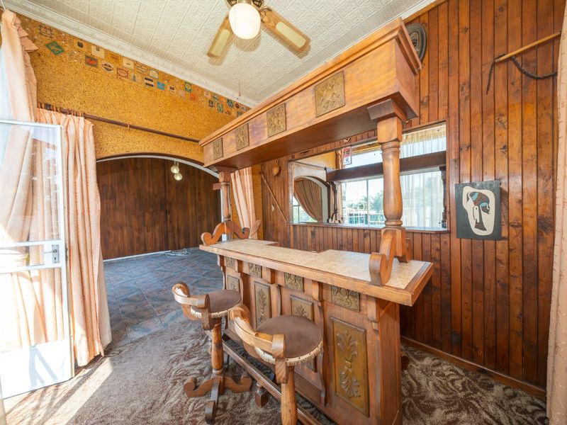 A dedicated bar area featuring timber wall paneling, a built-in bar counter, and a decorative pressed metal ceiling.