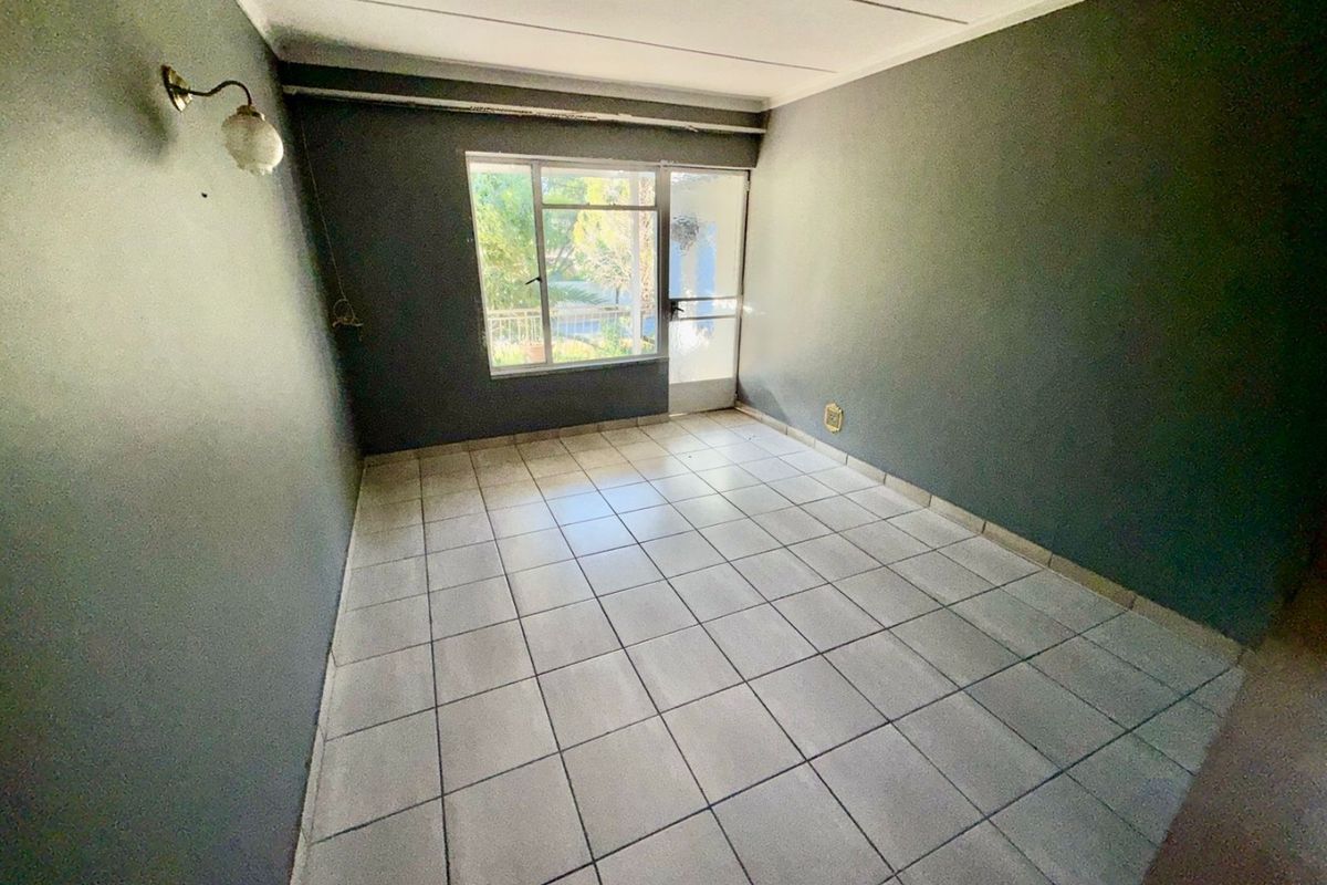 An empty living room featuring tiled flooring, dark painted walls, and direct access to an outdoor area through an aluminium door.