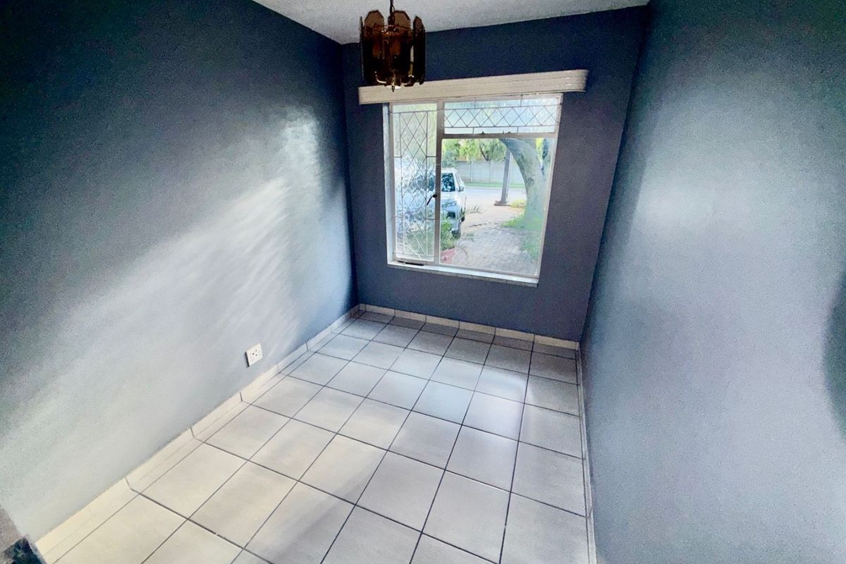 A vacant bedroom featuring tiled flooring, dark blue walls, and a leaded glass window providing natural light.