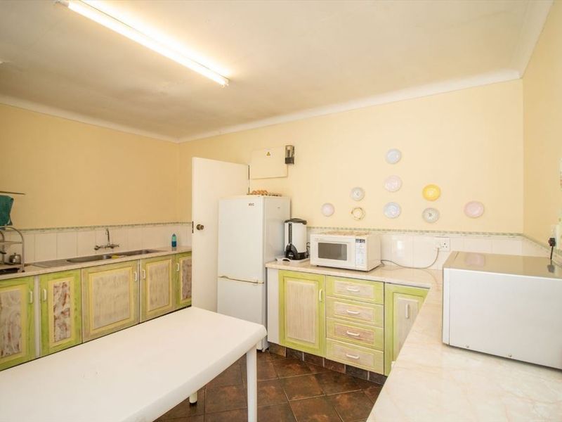 A functional kitchen featuring dated cabinetry, laminate countertops, a tiled backsplash, and a stainless steel sink, offering potential for a modern renovation.