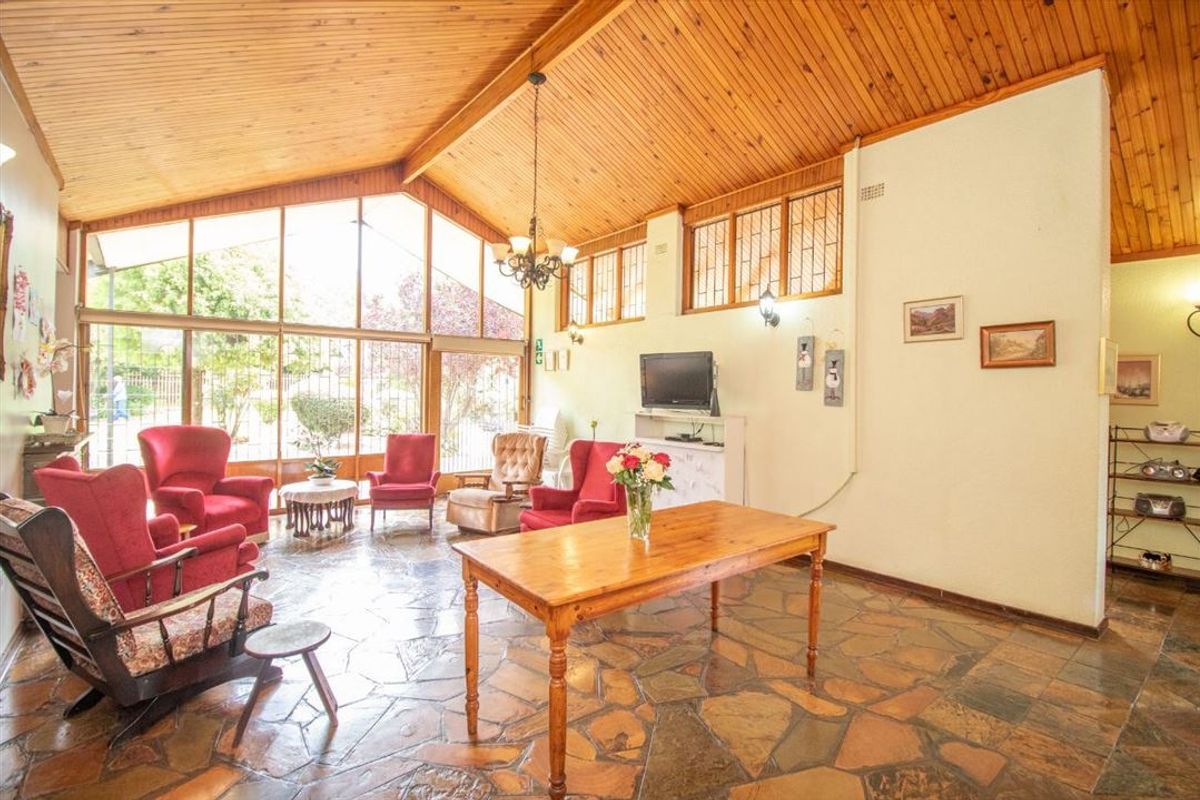 Spacious living area featuring a vaulted timber ceiling, unique flagstone flooring, and expansive windows that provide ample natural light.