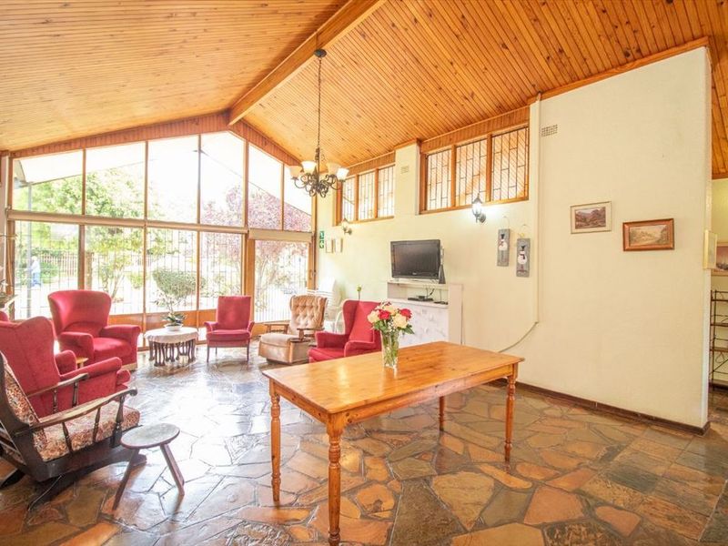 Spacious living area featuring a vaulted timber ceiling, unique flagstone flooring, and expansive windows that provide ample natural light.