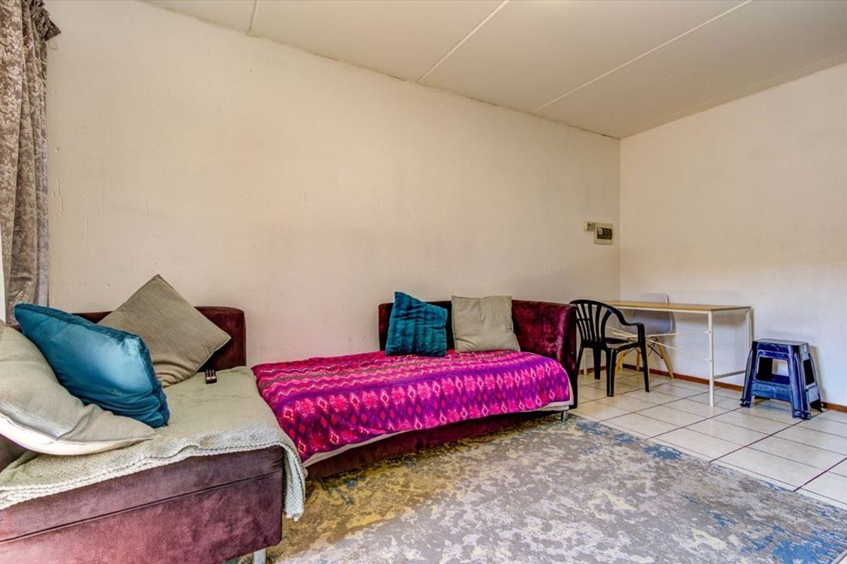 A living area featuring tiled flooring and plain walls, offering a functional space ready for modernization and aesthetic updates.