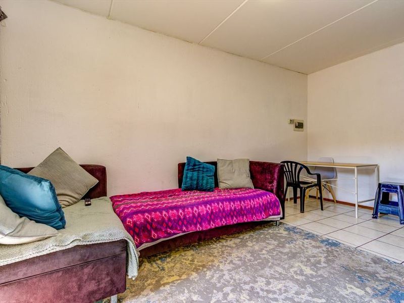 A living area featuring tiled flooring and plain walls, offering a functional space ready for modernization and aesthetic updates.
