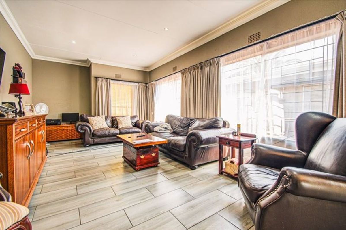 Spacious living room featuring modern tiled flooring, recessed ceiling lighting, and large sliding glass doors providing access to the exterior.