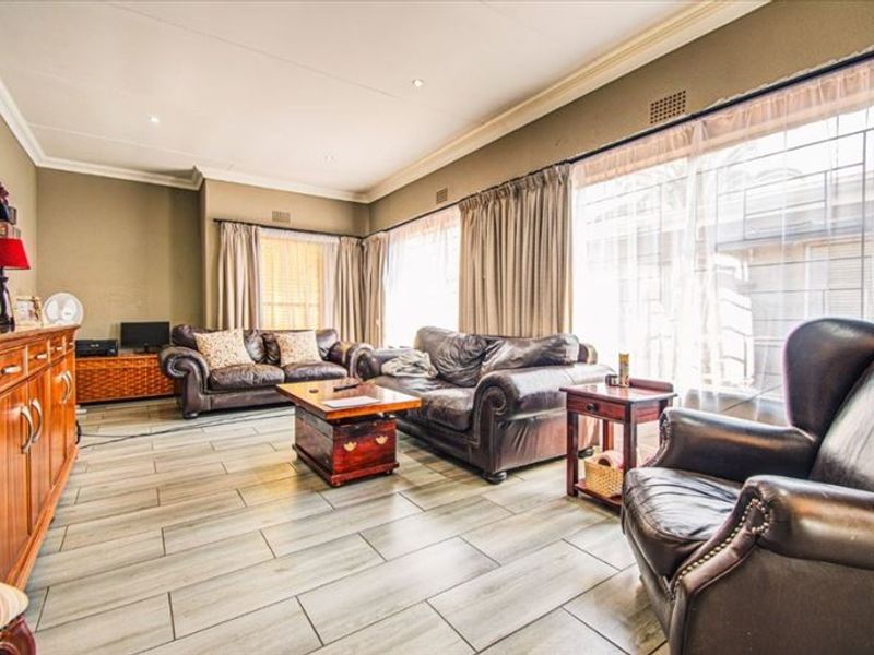 Spacious living room featuring modern tiled flooring, recessed ceiling lighting, and large sliding glass doors providing access to the exterior.
