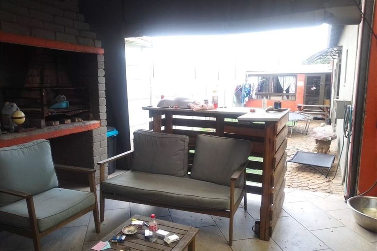 Covered outdoor patio area featuring a built-in brick braai and tiled flooring, providing a functional space for outdoor entertaining.