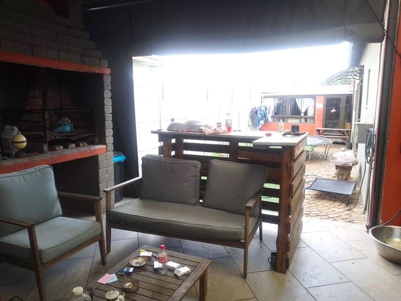 Covered outdoor patio area featuring a built-in brick braai and tiled flooring, providing a functional space for outdoor entertaining.