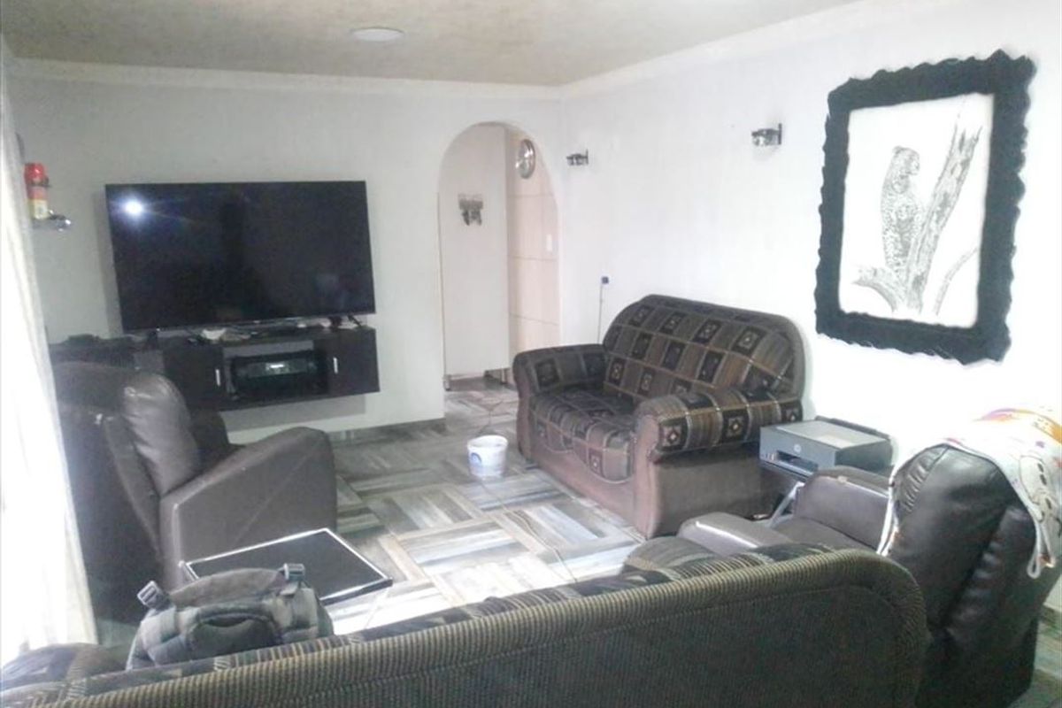 A living room featuring tiled flooring, an arched doorway leading to another area, and recessed ceiling lighting.