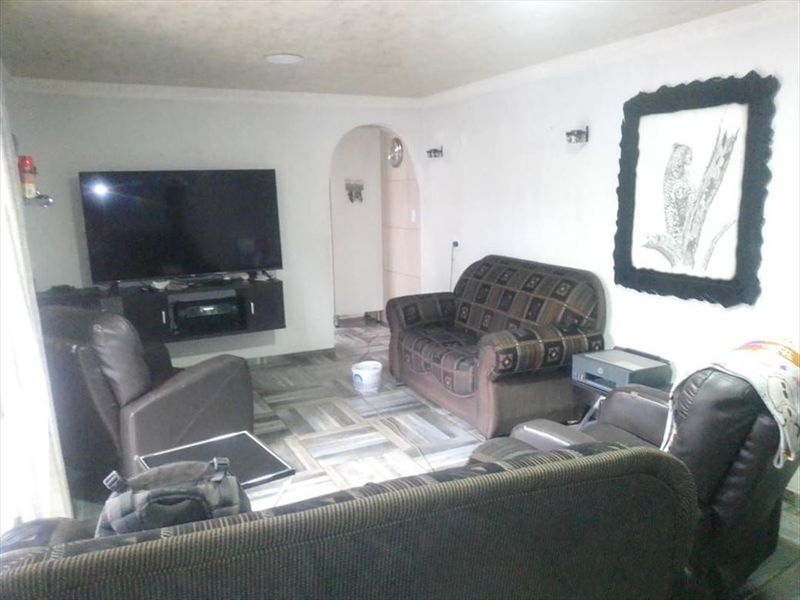 A living room featuring tiled flooring, an arched doorway leading to another area, and recessed ceiling lighting.
