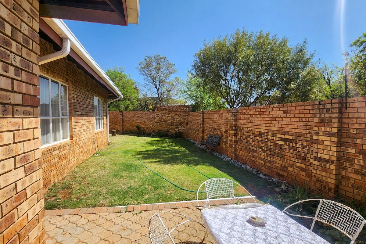 A private rear garden featuring a paved patio area, a well-maintained lawn, and secure brick boundary walls.