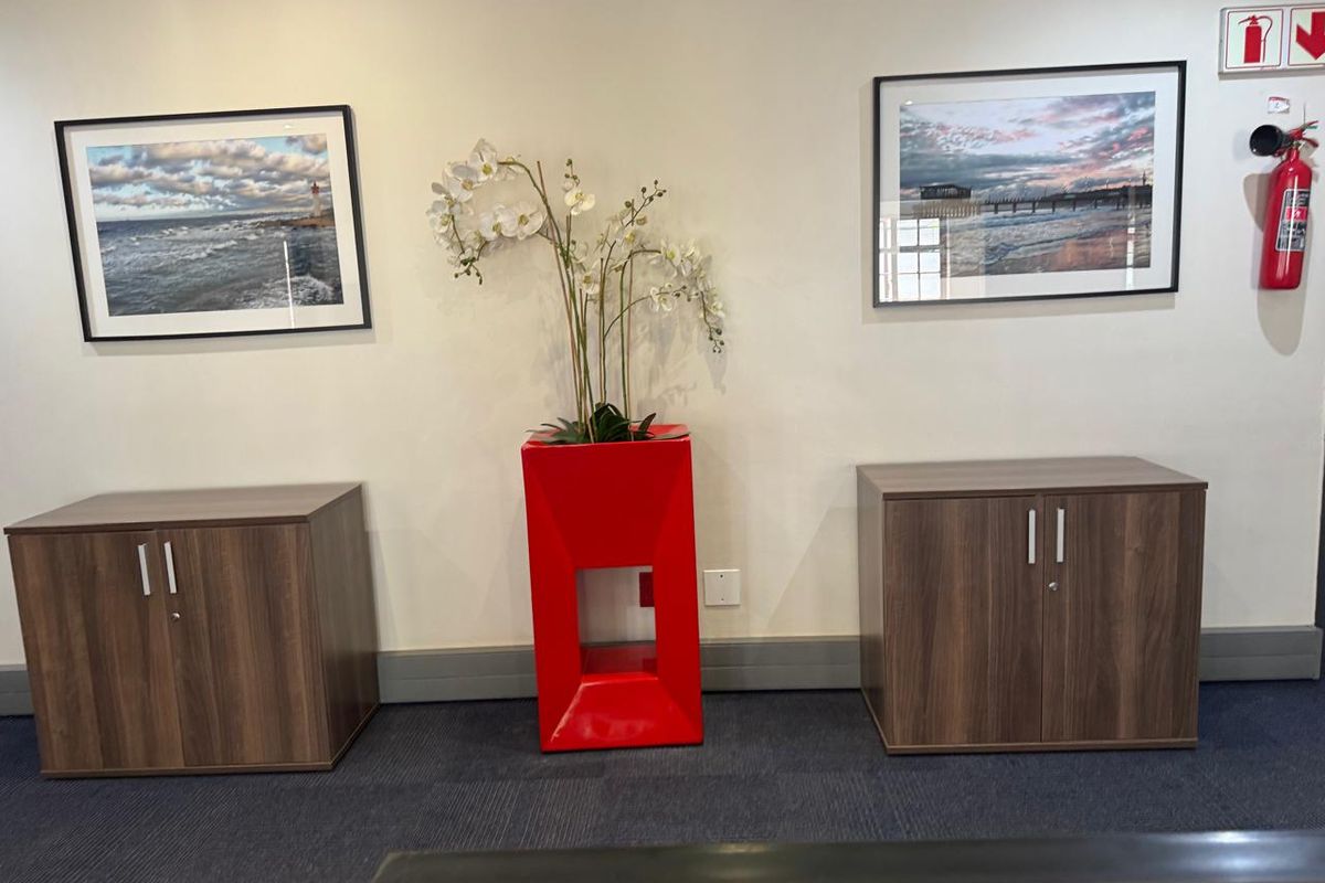 A professional office space featuring neutral walls, carpeted flooring, and wall-mounted fire safety equipment.
