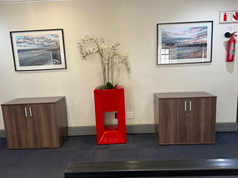 A professional office space featuring neutral walls, carpeted flooring, and wall-mounted fire safety equipment.