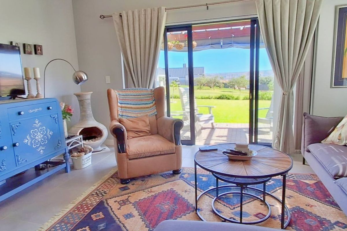 A comfortable living room featuring tiled flooring and large sliding glass doors that provide direct access to the outdoor patio and garden area.