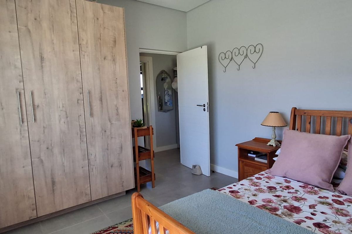 A well-maintained bedroom featuring light wood-finish built-in wardrobes, neutral wall tones, and tiled flooring, providing a clean and functional living space.