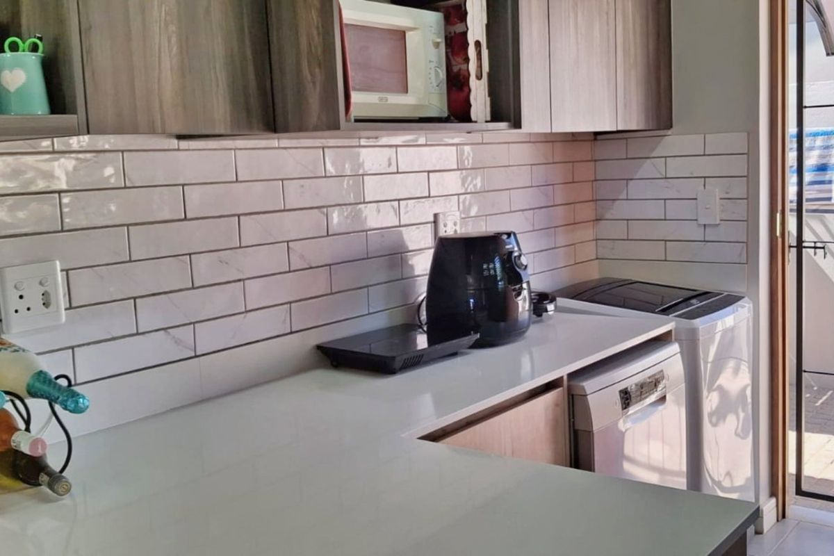 Modern kitchen featuring subway tile backsplash, quartz countertops, and built-in cabinetry with direct access to an outdoor area via a security gate.