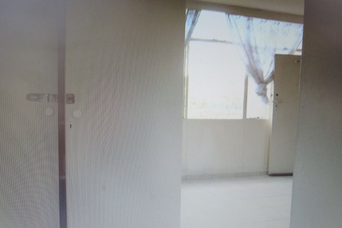 A vacant bedroom featuring tiled flooring and a large window, providing natural light to the space.