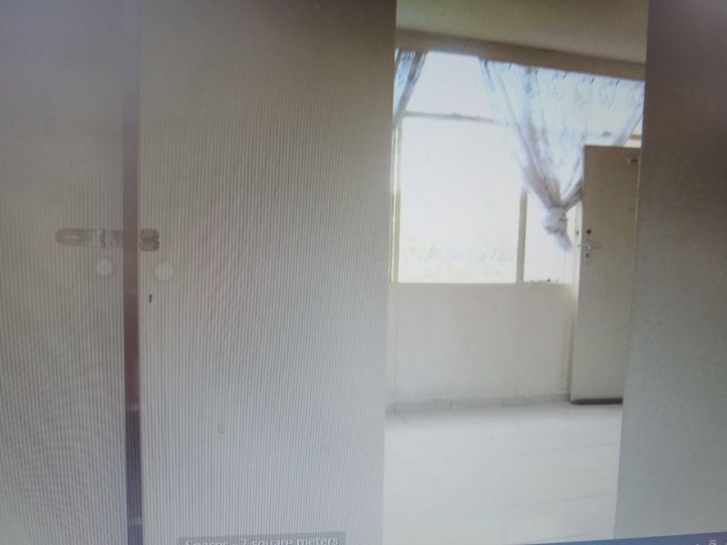 A vacant bedroom featuring tiled flooring and a large window, providing natural light to the space.