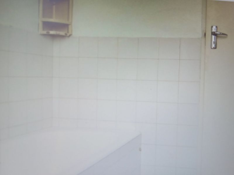 A basic bathroom featuring white wall tiles and a built-in wall cabinet, requiring cosmetic updates to improve its overall condition and appeal.