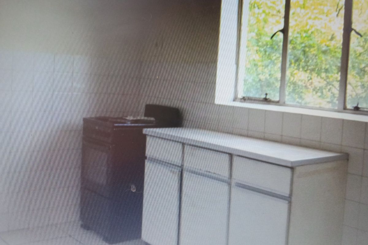 A compact kitchen featuring basic built-in cabinetry, a tiled splashback, and a freestanding stove, offering a functional space ready for modernization.