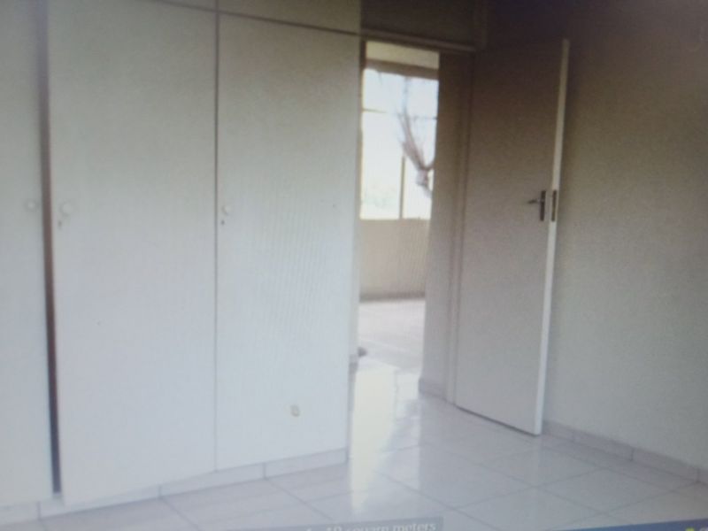 An empty bedroom featuring built-in cupboards and tiled flooring, offering a blank canvas for personalization.